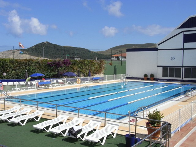 Piscina semi-olímpica exterior del Club Kaieder con tumbonas y montañas al fondo